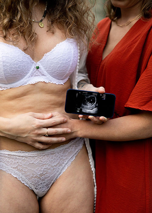 un couple de femmes tiennent un téléphone pour annoncer une grossesse