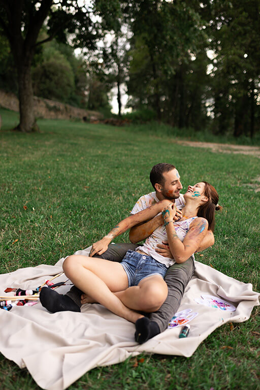 un couple joue avec de la peinture assis dans l'herbe