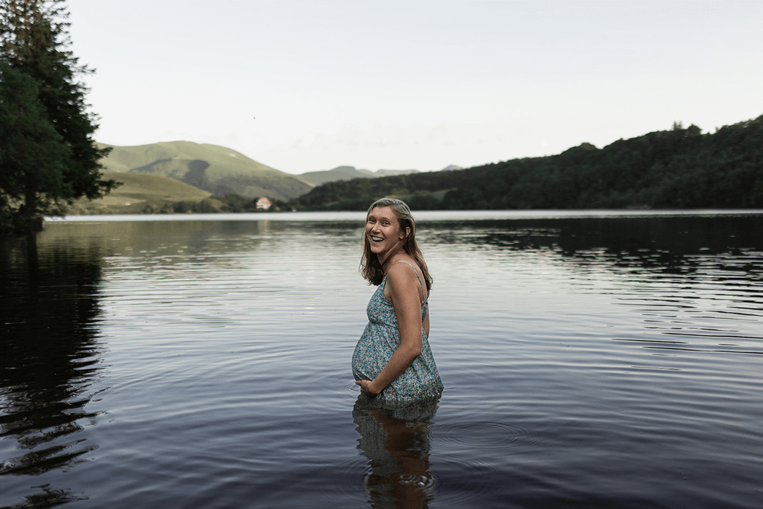 Une femme épanouit lors d'une séance photo de grossesse dans un lac d'Auvergne