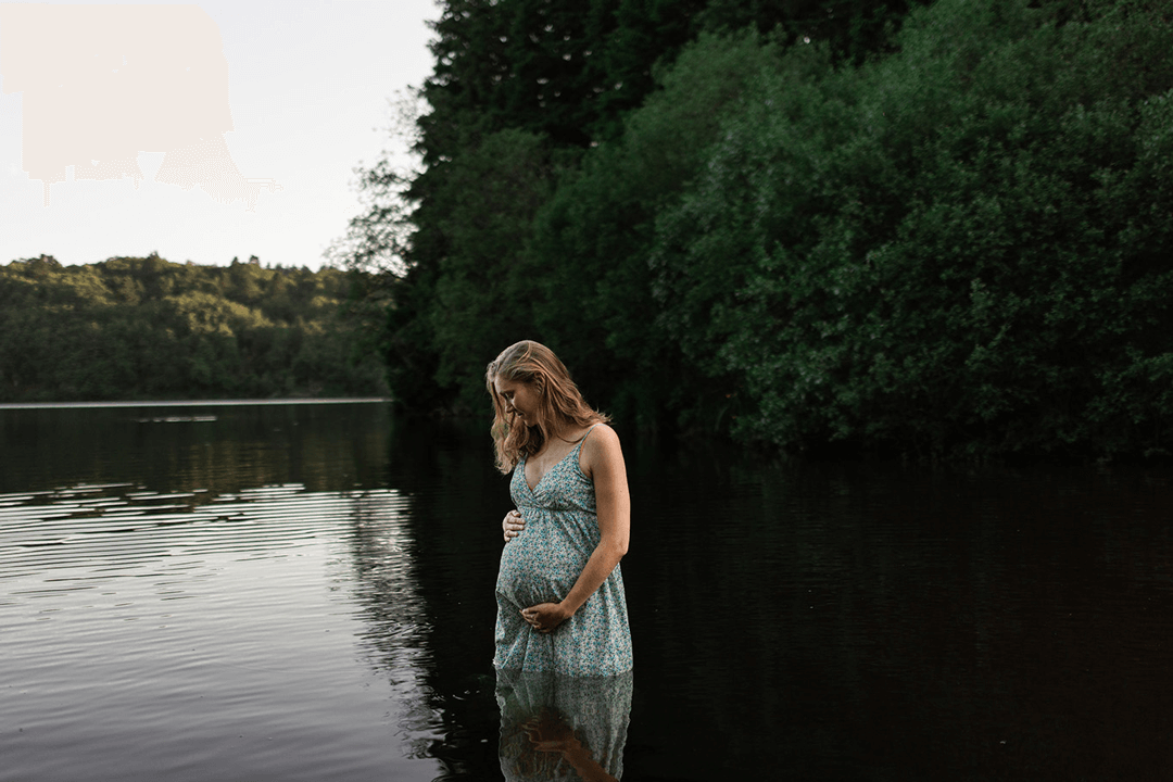 Une femme prend la pause lors d'une séance photo de grossesse dans un lac d'Auvergne