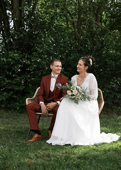 un couple de mariés assis sur un banc pendant leur cérémonie
