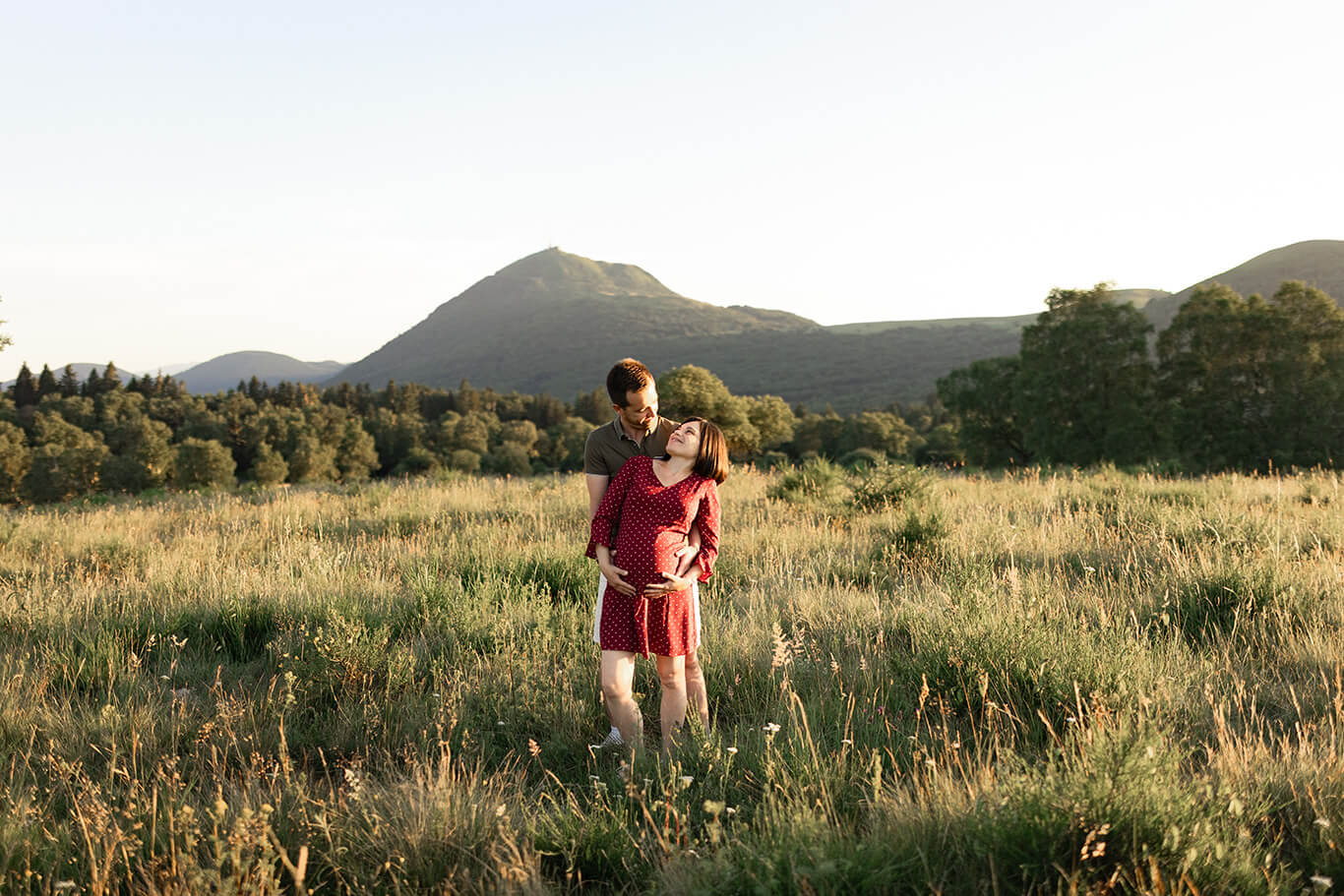 un couple dont la femme enceinte prend la pause devant le Puy-de-Dôme