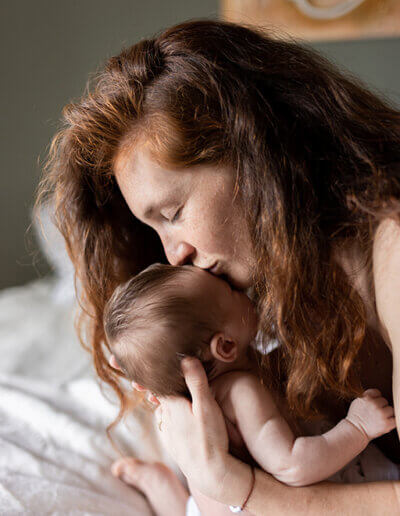 une femme dépose un baiser sur le front de son bébé