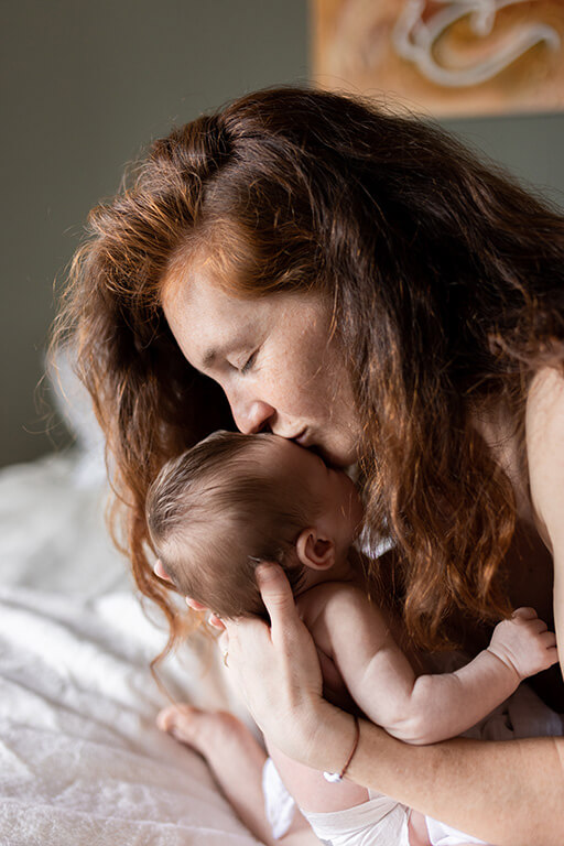 Une femme fait un bisous sur la tête de son bébé
